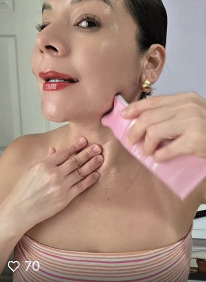 Woman gliding the gua sha tube along her jaw while holding her neck