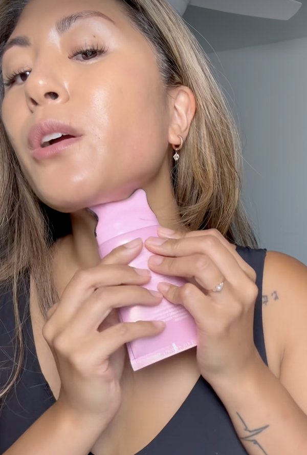 Woman gliding the gua sha tube up the front of her neck